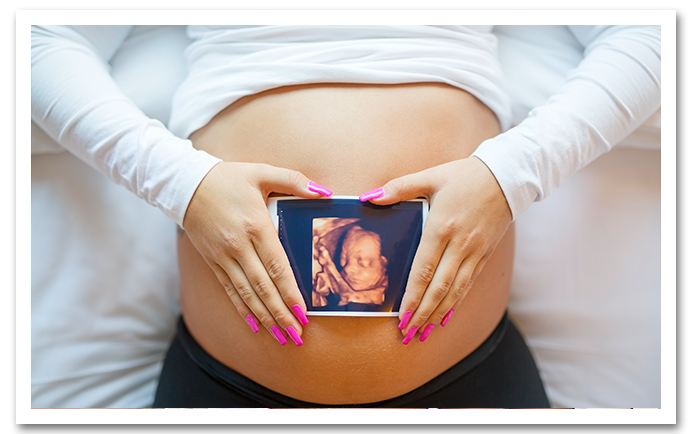 Woman holding ultrasound over belly